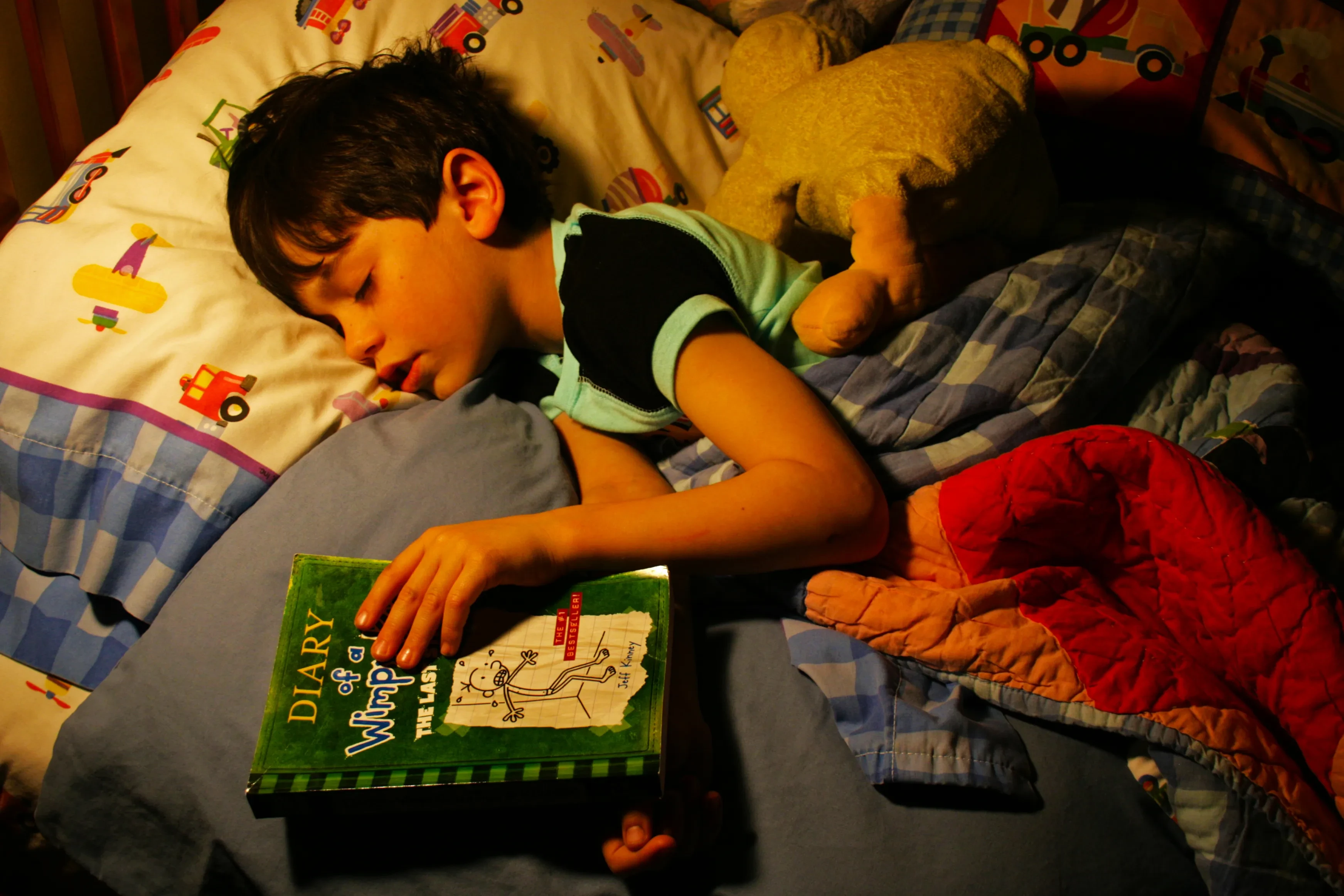 Anak membaca buku di tempat tidur menjelang tidur
