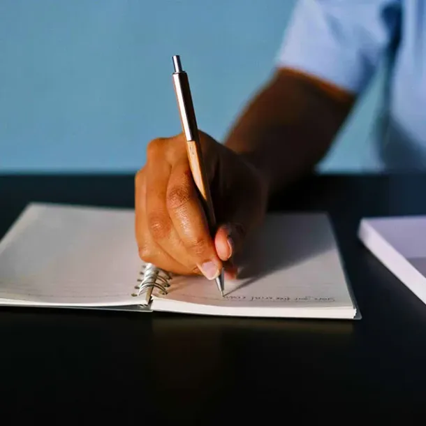 Tangan menulis dengan pulpen di atas kertas