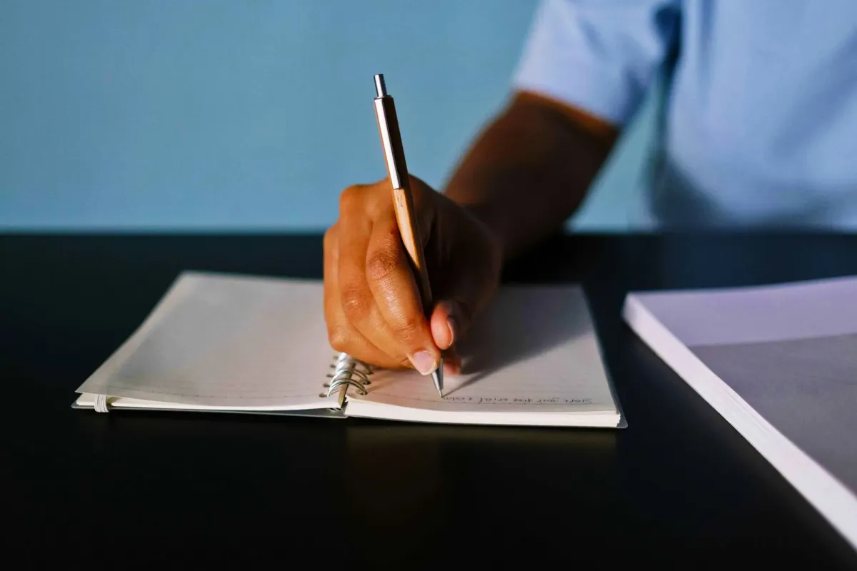 Tangan menulis dengan pulpen di atas kertas