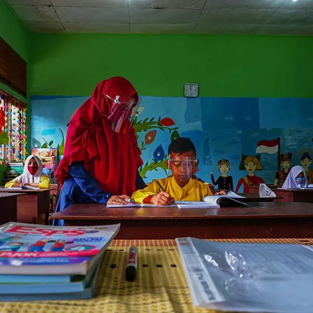 Guru Indonesia membimbing murid membaca di kelas
