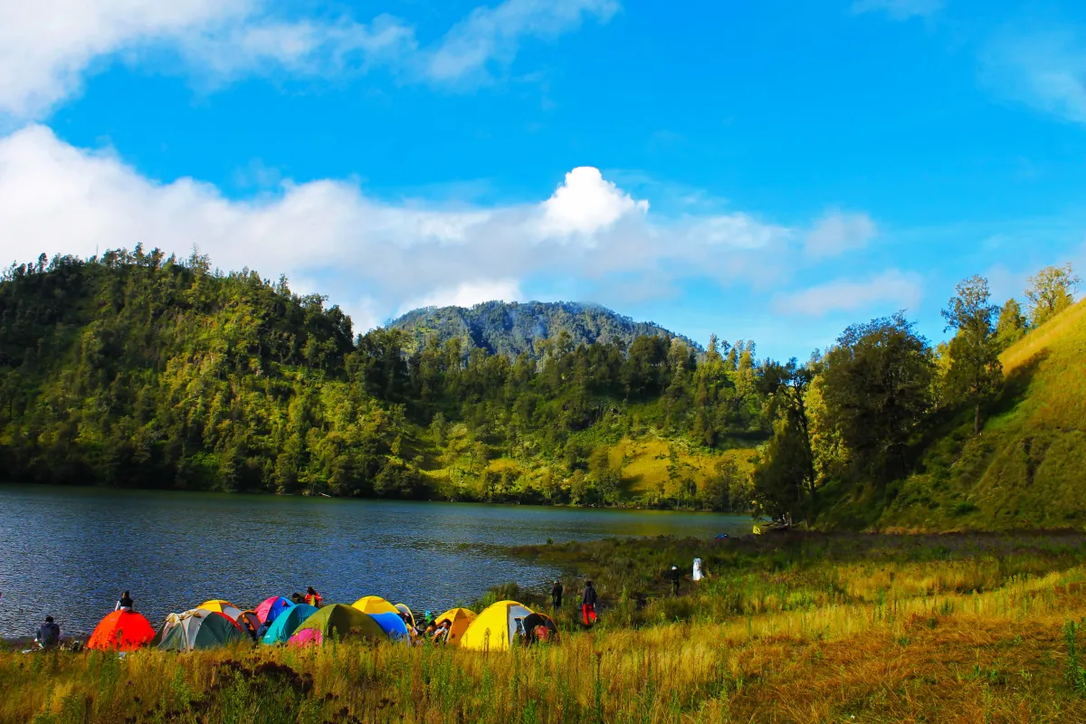 Pemandangan tenang Danau Ranu Kumbolo dengan tenda-tenda di tepi danau, menggambarkan suasana healing di alam pegunungan
