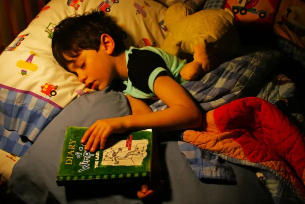 Anak tertidur memeluk buku setelah sesi read-aloud sebelum tidur