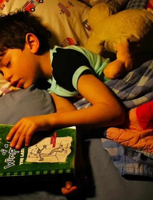 Anak tertidur memeluk buku setelah sesi read-aloud sebelum tidur