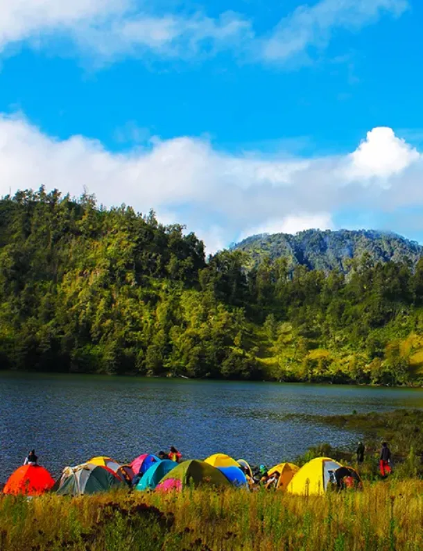 Pemandangan tenang Danau Ranu Kumbolo dengan tenda-tenda di tepi danau, menggambarkan suasana healing di alam pegunungan