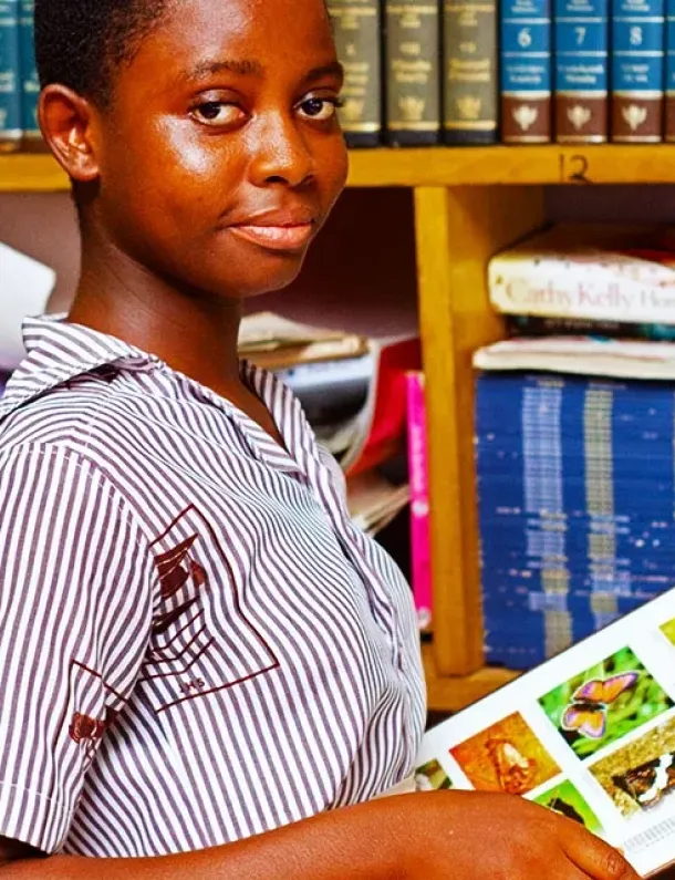 Tangan mengambil buku dari rak perpustakaan—visual memilih buku yang tepat.