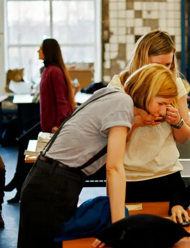 Tiga rekan kerja berdiskusi fokus di depan laptop.