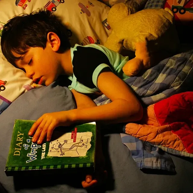 Anak tertidur memeluk buku setelah sesi read-aloud sebelum tidur