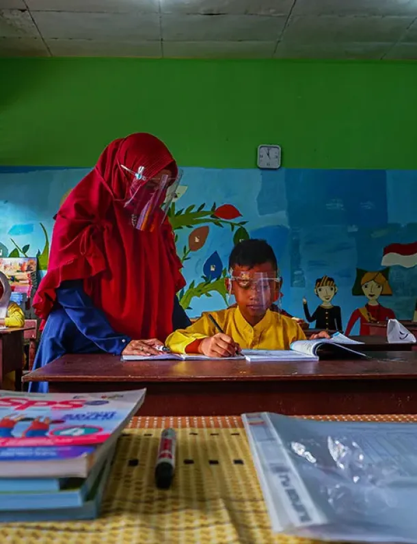 Guru Indonesia membimbing murid membaca di kelas