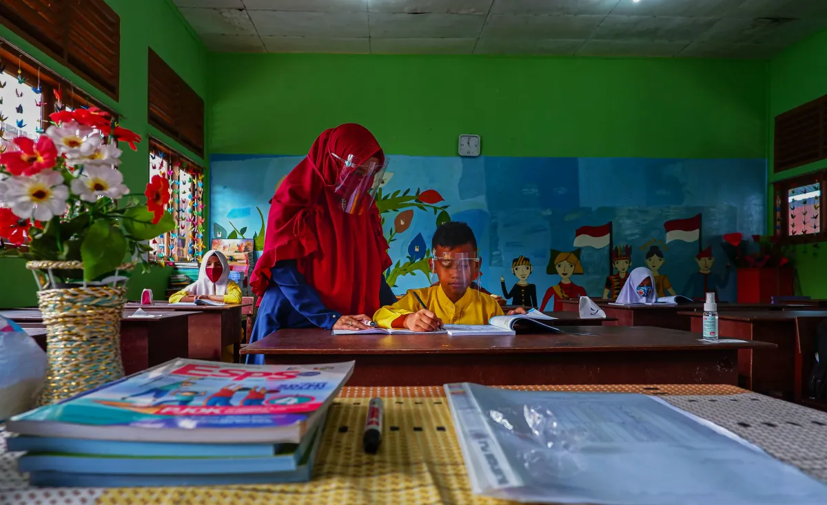 Guru Indonesia membimbing murid membaca di kelas