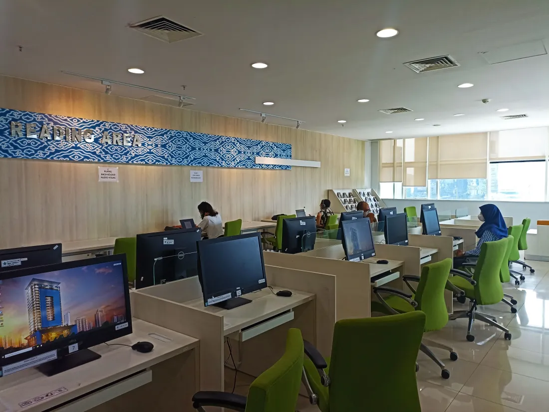 Area baca Perpustakaan Nasional RI—deretan meja, kursi, dan jendela besar yang terang