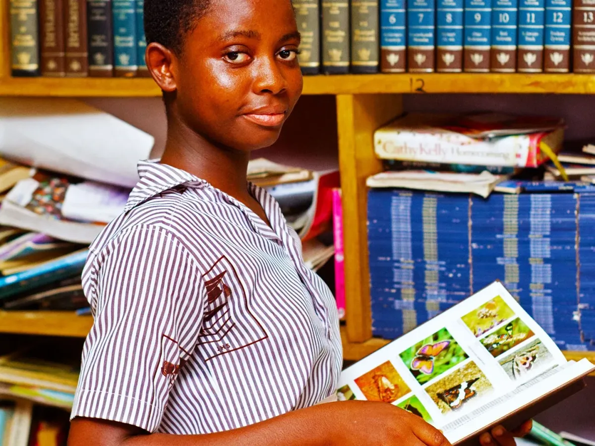 Tangan mengambil buku dari rak perpustakaan&mdash;visual memilih buku yang tepat.