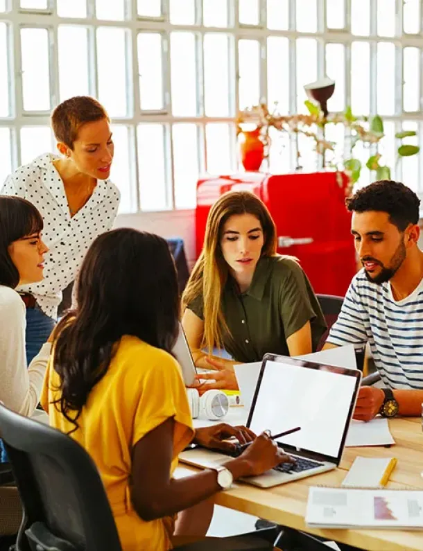 Tiga rekan kerja berdiskusi fokus di depan laptop.