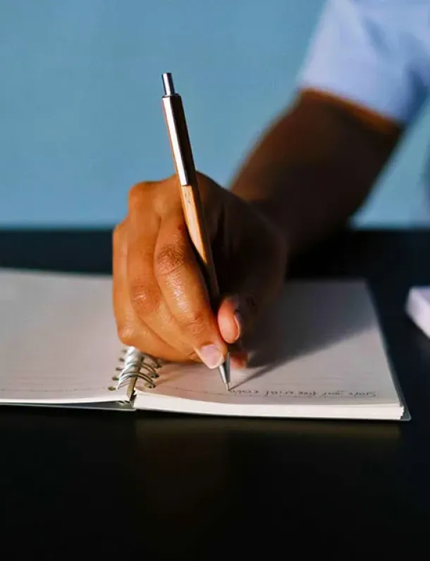 Tangan menulis dengan pulpen di atas kertas