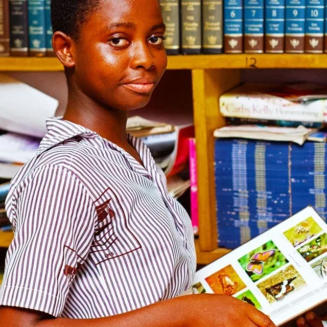 Tangan mengambil buku dari rak perpustakaan—visual memilih buku yang tepat.